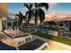 Waterfront backyard with a view of boats, lounge chairs, and tropical landscaping at sunset at 4930 60Th S Ave, St Petersburg, FL 33715