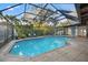 Screened in Pool with brick trim, stone floor, bushes visible through screen, and chairs at 6104 Dory Way, Tampa, FL 33615