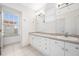 Bathroom featuring double sinks, white cabinetry, tiled floors, and view from the window at 615 Olive Tree Ct, Clearwater, FL 33756