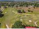 Expansive aerial view of a golf course with mature trees and manicured greens and sand traps at 7078 Lexington Cir, Brooksville, FL 34602