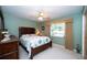 Cozy bedroom with a wooden bed frame, dresser, neutral carpet, and natural light from the window at 7078 Lexington Cir, Brooksville, FL 34602