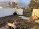 View of the backyard with a mix of wooden and chainlink fences, wood pile, and some overgrown grass at 8428 Paxton Dr, Port Richey, FL 34668