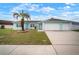 Inviting turquoise home with a two-car garage, well-kept lawn, and beautiful palm tree at 11248 Andy Dr, Riverview, FL 33569