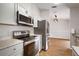 Open kitchen featuring stainless steel appliances, gray cabinets, granite countertops, and wood-look flooring at 11248 Andy Dr, Riverview, FL 33569