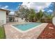 Beautiful pool surrounded by lush tropical landscaping and brick patio, perfect for outdoor enjoyment at 121 Shirley Dr, Largo, FL 33770