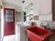 Laundry room with a red sink, white washer, a red door, and overhead shelving at 12845 95Th N St, Largo, FL 33773