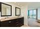 Bathroom featuring double sinks with wood cabinets, tile floors, and a view of the water at 1540 Gulf Blvd # Ph7, Clearwater Beach, FL 33767