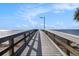 Community pier with gray wood and metal railings leading to the ocean under a blue sky at 3266 Mangrove Point Dr, Ruskin, FL 33570