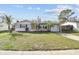 Inviting single-story home featuring a well-manicured lawn, a yellow door, and small palm trees at 3934 Moog Rd, Holiday, FL 34691