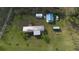 Aerial view of a single-story home with multiple outbuildings on a spacious lot with mature trees at 10519 Shalimar St, New Port Richey, FL 34654