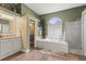 Bright bathroom featuring dual vanities, a soaking tub beneath a large window, and a glass-enclosed shower at 108 Rosana Dr, Brandon, FL 33511