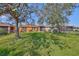 Lush backyard featuring a well-maintained lawn, mature trees, and a view of neighboring homes at 715 Parker Den Dr, Ruskin, FL 33570