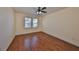 Bedroom with wood floors, ceiling fan and light, and two windows with blinds and a view of trees at 715 Parker Den Dr, Ruskin, FL 33570