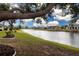 Scenic view of waterfront homes from lush backyard featuring large trees and manicured lawn at 2016 E View Dr, Sun City Center, FL 33573