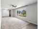 Open living room with large window, gray carpet, ceiling fan, and view of the front door at 2391 66Th S Ter, St Petersburg, FL 33712