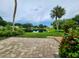 Scenic backyard view with stone pavers, pond, and landscaping at 821 Deleon Ct # 108, Dunedin, FL 34698