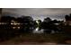 Nighttime view of a tranquil pond reflecting the surrounding houses and trees at 821 Deleon Ct # 108, Dunedin, FL 34698