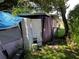 A cluttered backyard with a tarp, damaged shutters, and overgrown foliage at 5634 5Th N Ave, St Petersburg, FL 33710