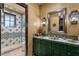 Elegant bathroom with green vanity, tile shower, and decorative mirror at 33642 Blanton Rd, Dade City, FL 33523