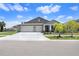 Gray house with 3-car garage and landscaped yard at 10704 Sage Canyon Dr, Riverview, FL 33578