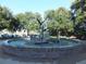 Circular fountain with bird sculpture and brick border, surrounded by trees at 109 Wateredge Ct, Safety Harbor, FL 34695