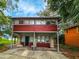 Two-story home with a red exterior, and a small front yard with a covered carport at 1414 7Th S St, St Petersburg, FL 33701