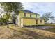Back view of the yellow house, showing the yard and some stonework at 553 Division St, Tarpon Springs, FL 34689