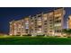 Night shot of the condo building showcasing illuminated windows and manicured lawn at 634 Edgewater Dr # 644, Dunedin, FL 34698