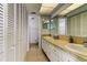 Bathroom featuring double sinks, tile countertops, and ample storage with the white shuttered cabinet doors at 403 Gulf Way # 504, St Pete Beach, FL 33706
