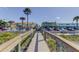 A beach access boardwalk leading to a vibrant beachfront area with commercial buildings and street parking at 403 Gulf Way # 504, St Pete Beach, FL 33706