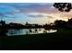 Peaceful sunset over a lake with palm trees and lush green grass at 6302 Pelican Creek Xing # A, St Petersburg, FL 33707