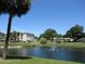 Scenic view of a community pond with a fountain, surrounded by lush greenery and residential buildings at 940 Virginia St # 107, Dunedin, FL 34698