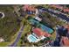 An aerial view of the condo community with pools and tennis courts amidst mature trees shows the amenities and recreational areas at 1806 Mariner Dr # 214, Tarpon Springs, FL 34689