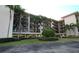 Exterior view of condo building with green space, palm trees, and covered parking at 1806 Mariner Dr # 214, Tarpon Springs, FL 34689