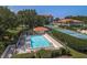 Aerial view of the community pool and tennis courts surrounded by verdant landscaping and mature trees at 1806 Mariner Dr # 214, Tarpon Springs, FL 34689