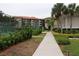 A tennis court with a manicured landscape path leading through a verdant, mature landscape in the condo community at 1806 Mariner Dr # 214, Tarpon Springs, FL 34689
