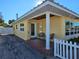 Bright yellow house with a covered entryway and a white picket fence at 108 11Th Ave, St Pete Beach, FL 33706