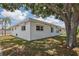 Single story home with white exterior, roll-down shutters, and large tree at 5396 Acacia N Trl, Pinellas Park, FL 33782