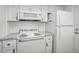 White kitchen features a microwave, stovetop and refrigerator at 5396 Acacia N Trl, Pinellas Park, FL 33782