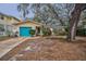 Charming single-story home with teal garage door, landscaping, and a large tree at 335 Tucker St, Safety Harbor, FL 34695