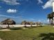 Beachfront view with thatched palapas providing shade on the grassy area at 1460 Gulf Blvd # 1212, Clearwater Beach, FL 33767