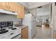 Kitchen featuring light wood cabinets, white appliances, stone countertops and access to the living room at 6201 2Nd E St # 73, St Pete Beach, FL 33706