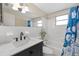 Clean bathroom with marble vanity, white subway tile, and blue shower curtain at 4031 Reggie Dr, Holiday, FL 34691