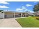 Tan single story home with attached garage, landscaped lawn, and a yellow front door at 4031 Reggie Dr, Holiday, FL 34691