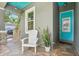 Inviting front porch with teal door and a white adirondack chair at 131 Pennsylvania Ave, Palm Harbor, FL 34683