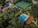 Aerial view of a community pool and tennis courts surrounded by lush greenery and residential homes at 3482 Rolling Trl, Palm Harbor, FL 34684