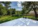 Green backyard with a white patio, wooden fence, and lots of natural foliage, perfect for outdoor activities at 3482 Rolling Trl, Palm Harbor, FL 34684