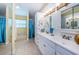 Bright bathroom featuring a double vanity with a white cabinet, decorative mirrors, and tiled floors at 3482 Rolling Trl, Palm Harbor, FL 34684