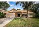 Charming single-story home featuring a brick facade, lush green lawn, and two-car garage at 3482 Rolling Trl, Palm Harbor, FL 34684