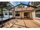 View of the home's screened in porch with an umbrella table and sliding door access to the home's interior at 3482 Rolling Trl, Palm Harbor, FL 34684